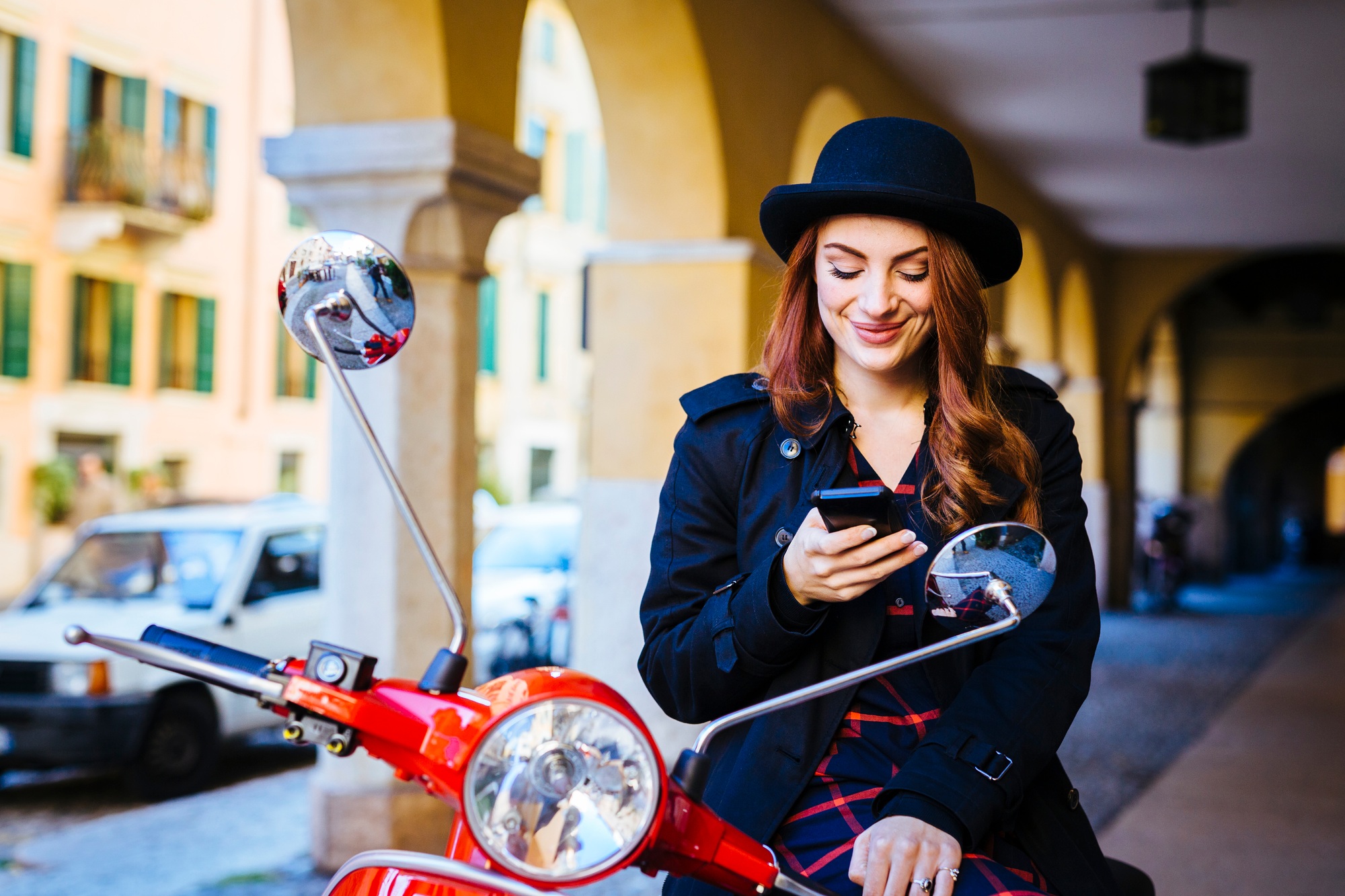 Italy, Verona, young woman with scooter looking at cell phone