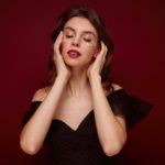 Portrait of charming young brown haired female with evening makeup