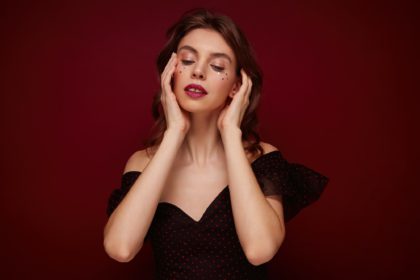 Portrait of charming young brown haired female with evening makeup