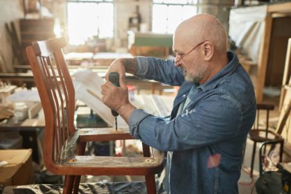 Senior man repairing furniture in carpentry workshop